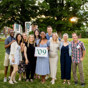 people standing on grass holding a sign that says '09