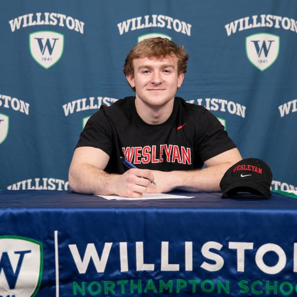 male student sitting at table with Williston northampton school logo