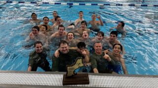 team in pool posing with trophy