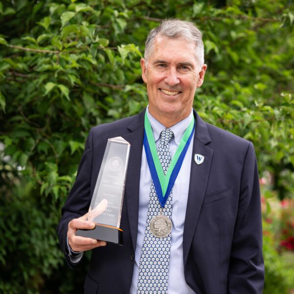 man posing on lawn with trophy