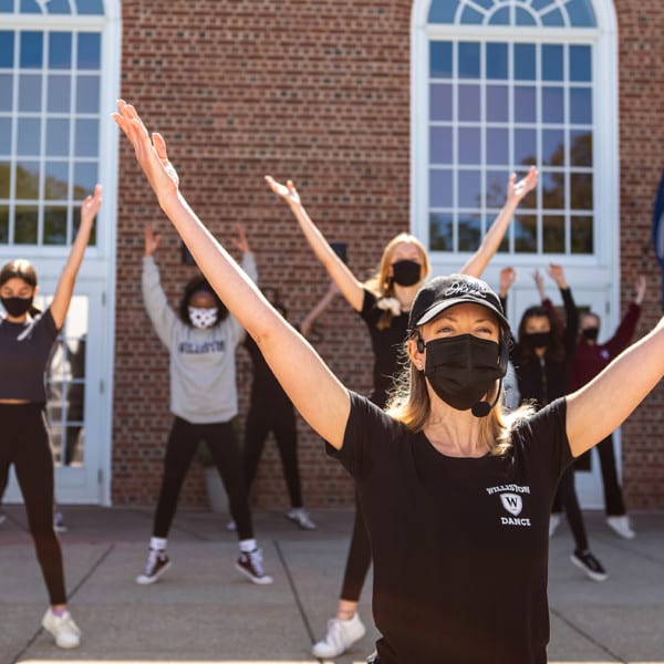 dancers in masks arms stretched up