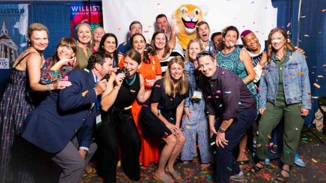 school alumni post in front of a backdrop with confetti