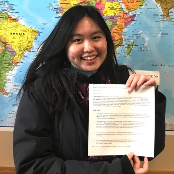 girl holding paper in front of map