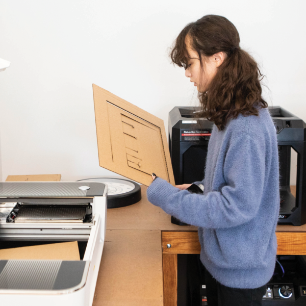 girls using a laser cutter to shape cardboard