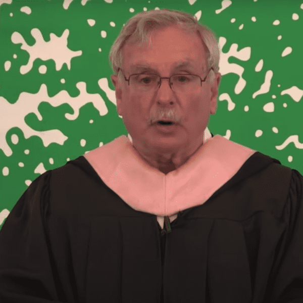 man standing at podium in black robe at graduation